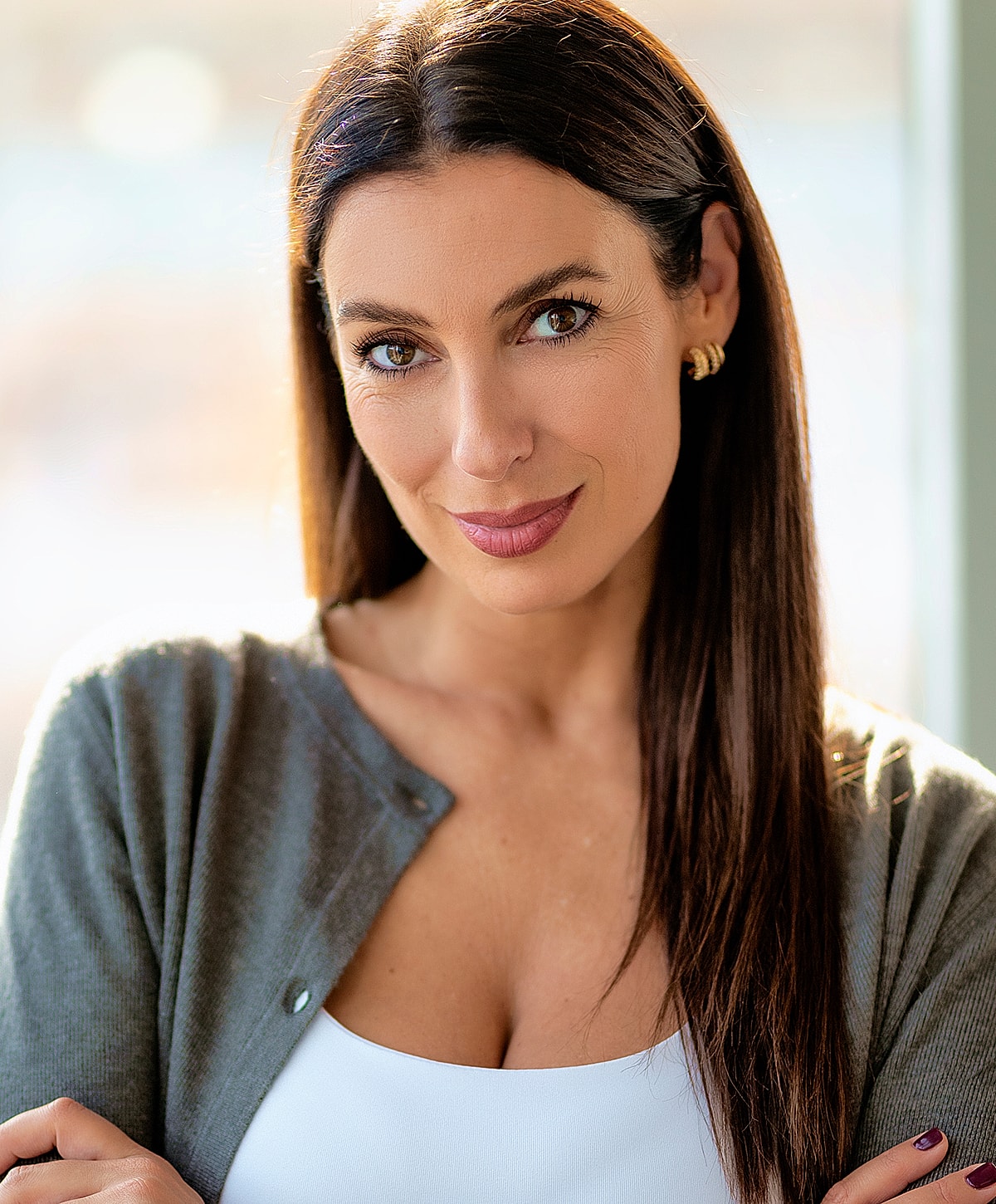 Smiling woman with long hair in a cardigan.