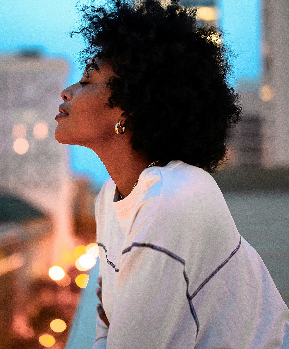 Profile of a woman with curly hair at dusk.